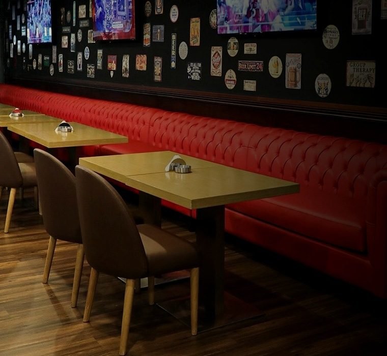 Red leather banquette seating and the sticker wall at Adam's Beer Kitchen JVC